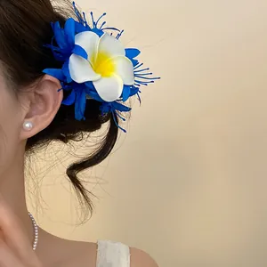 Primo piano di una clip per capelli a fiore di frangipane bohémien blu e bianca
