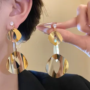 Close-up of elegant gold geometric drop earrings with sparkling zircon and smooth finish