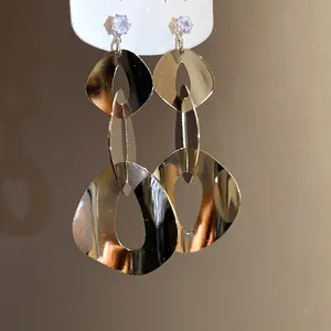 Detailed close-up showing the metallic luster of geometric silver tassel earrings with zircons