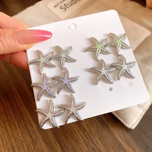 Primer plano de delicados pendientes de estrella de mar con esmalte en varios colores pastel