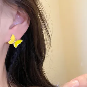 Detalle de un pendiente de mariposa de esmalte amarillo usado en el lóbulo de la oreja