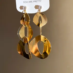 Detailed view of shiny gold geometric dangle earrings with sparkling zircon studs.