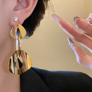 Close-up of elegant gold geometric dangle earrings with zircon studs for women.