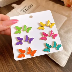 Vista detallada de seis pares de pendientes de mariposa de colores en un cartón