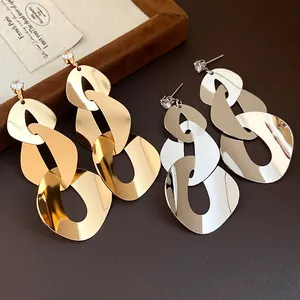 Close-up of gold and silver geometric link earrings with zircon studs and smooth finish.