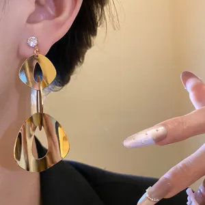 Detail of fashion geometric gold smooth dangle earrings with zircon stud for women.