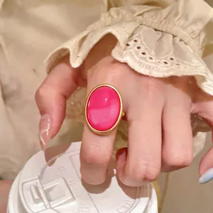 Macro view of a statement oval resin ring in hot pink with a gold-tone minimalist border.