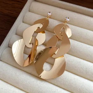 Close-up of gold geometric link earrings with clear zircon stud in velvet tray.
