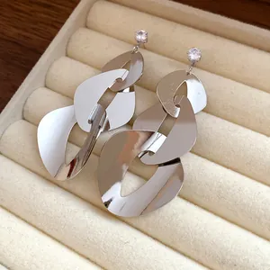 Detailed macro view of silver geometric link earrings with zircon studs on a velvet jewelry tray