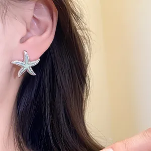 Primer plano de elegantes pendientes de estrella de mar con esmalte verde menta