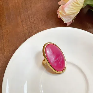 Close-up of elegant oval pink resin ring on a white saucer background