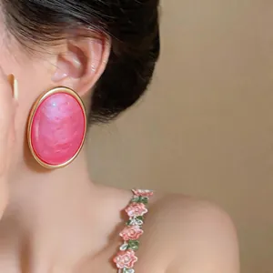 Close-up macro shot of a stylish large pink resin oval stud earring worn on an ear