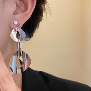 Close-up detail of minimalist silver geometric dangle earrings featuring clear zircon studs