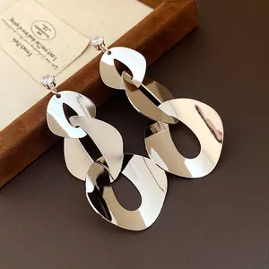 Close-up detail of silver-toned geometric drop earrings with polished organic metal links