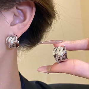 Detailed view of vintage textured C-shaped silver stud earrings on ear and hand