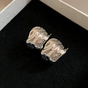 Macro view showing the crumpled metallic texture of silver C-shape stud earrings