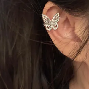 Close-up macro detail of a sparkling silver zircon butterfly ear cuff worn on an ear