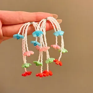 Detailed view of colorful handmade flower beaded tassel earrings with white seed beads.