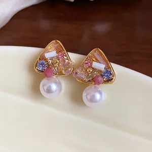 Close-up of French vintage 18k gold plated stud earrings with large pearls and colorful crystals
