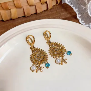 Primo piano di orecchini a conchiglia dorati con stelle marine, perle e perline blu.