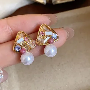 Close-up of French vintage gold-plated earrings with colorful crystals and pearls.
