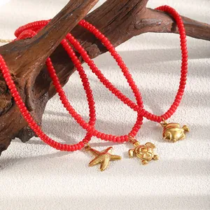 Detailweergave van rode glazen kralenkettingen met gouden zeester- en schildpadhangers.