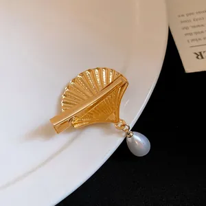 Close-up view of a vintage gold shell hair clip with an elegant teardrop pearl drop