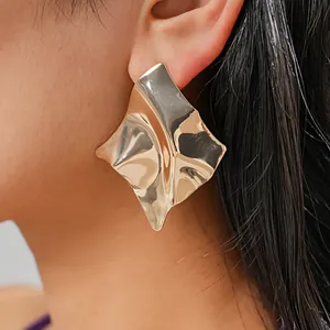 Detailed close-up showing the metallic texture of a golden irregular geometric stud earring