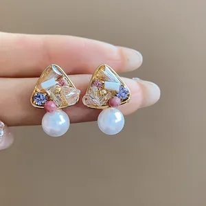 Macro view of vintage 18k gold plated earrings with glass pearls and colorful stones