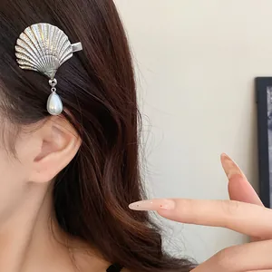 Detailed close-up view of a silver shell hair clip with a white pearl drop pendant.