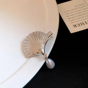 Detailed close-up showing the silver seashell texture and dangling waterdrop pearl on a hair clip