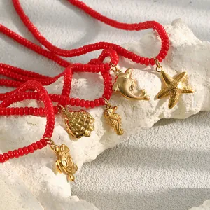 Detail van rode glazen kralenkettingen met gouden zeedierhangers zoals zeester en schildpad.