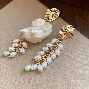 French vintage gold shell and pearl fringe earrings displayed on a textured background