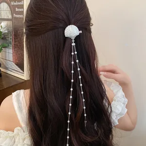 Detailed view of an elegant shell hair clip with long pearl tassels on wavy hair