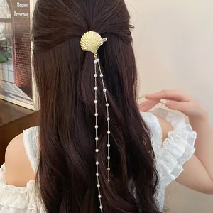 Detail view of a vintage gold shell hair clip with elegant long pearl dangles on dark hair