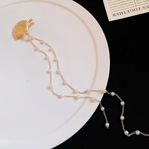 Detailed macro view of the gold shell hair clip with long elegant pearl chain tassels