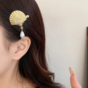 Detail shot of a vintage gold shell hair clip featuring a dangling teardrop pearl