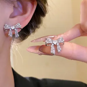 Elegant 18k gold plated bow earrings with zircon and pearls on a model.