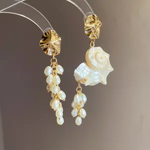 Detailed view of French retro shell and pearl tassel asymmetric earrings in gold
