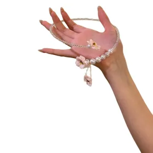 Collier choker élégant avec fleurs roses et glands en perles présenté sur la main.