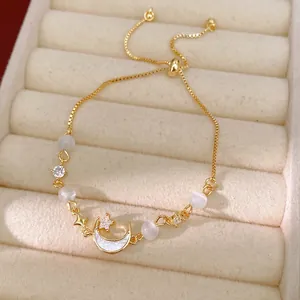 Dainty gold adjustable moon and star bracelet featuring white cat eye stones and zircons