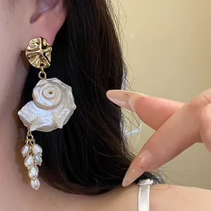 Close-up of French vintage gold shell and pearl tassel earrings on ear