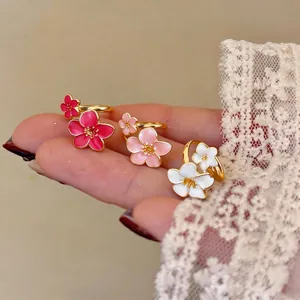 Elegante set di anelli con fiori in smalto rosa, bianco e rosso con una finitura dorata.