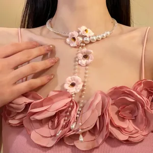 Vue détaillée d'un collier élégant en fleurs de tissu rose et perles avec longue pampille.