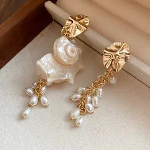 Close-up detail of vintage shell and pearl tassel earrings with gold-tone hammered finish