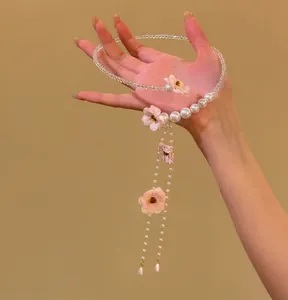 Détail d'un collier de fleurs roses avec pompons de perles élégants et perles fines.