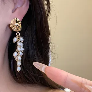 Detailed view of French vintage gold shell and white pearl tassel earrings worn by a model