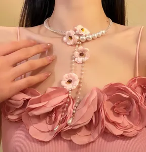 Détail d'un collier de perles à pampilles de fleurs roses, esthétique vintage et douce
