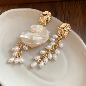 Detailed view of vintage shell and pearl tassel earrings resting on a ceramic dish
