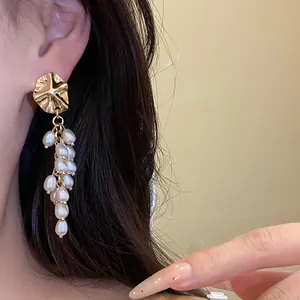 Detail shot of elegant vintage gold shell pearl tassel earrings worn on model ear